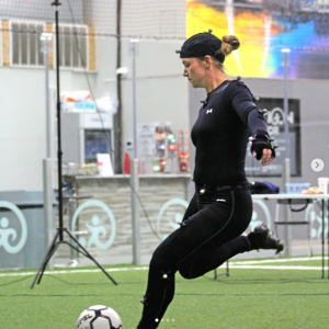 Woman kicking a soccer ball with motion capture suit