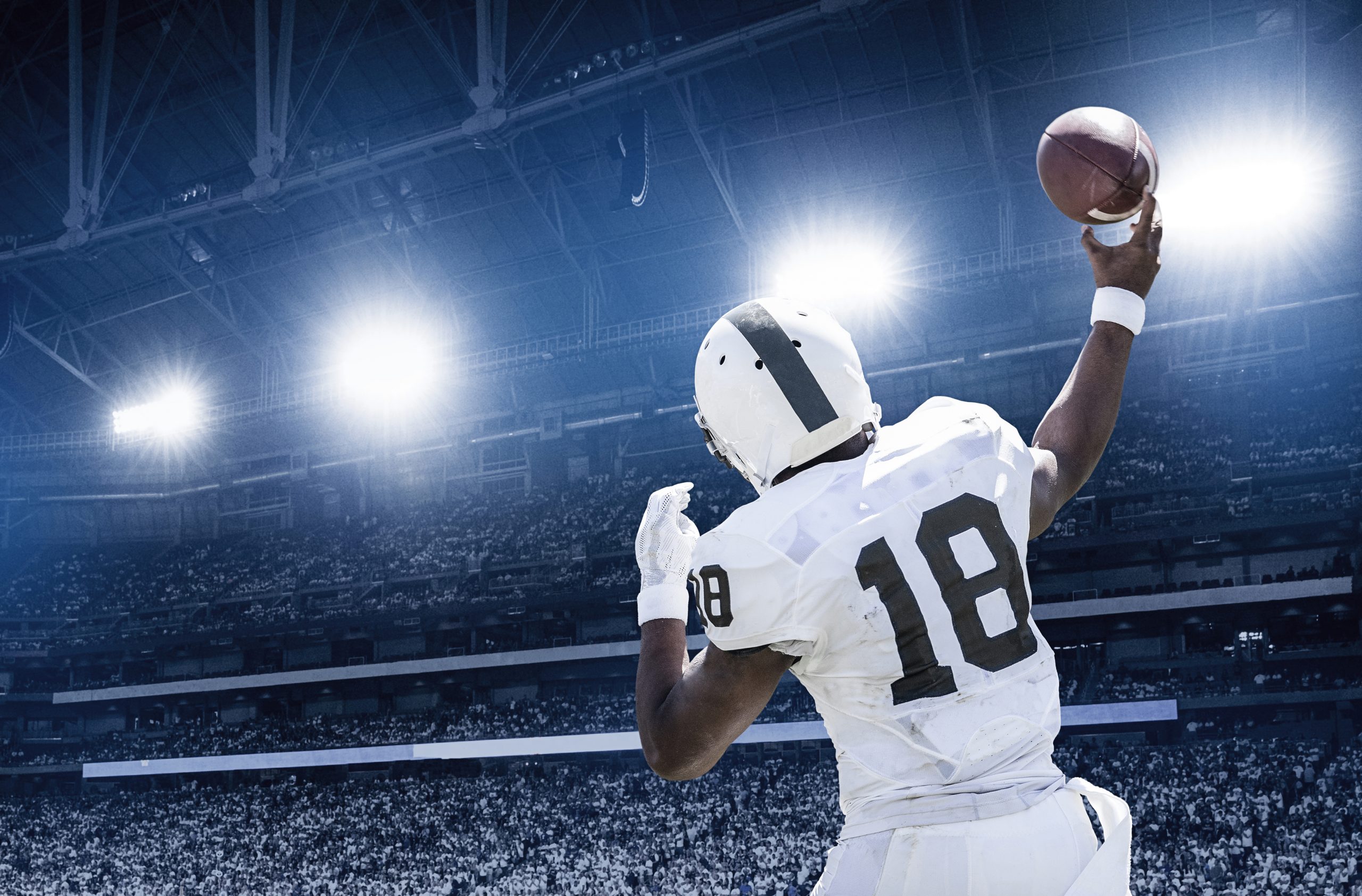 quarterback in a packed stadium about to throw a brown football