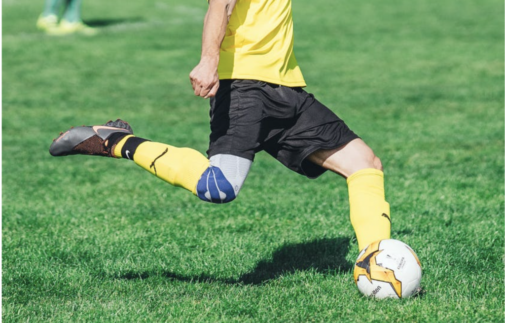 Man in yellow about to kick a soccer ball