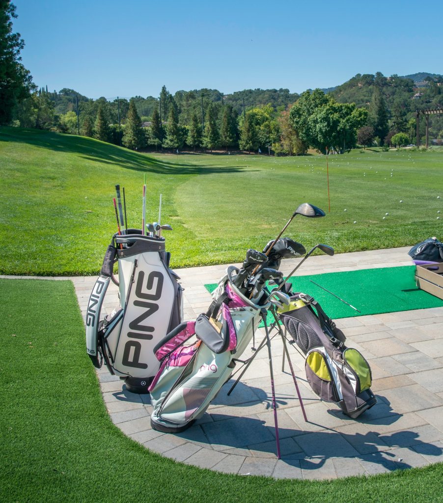 Golf clubs sitting at a driving range