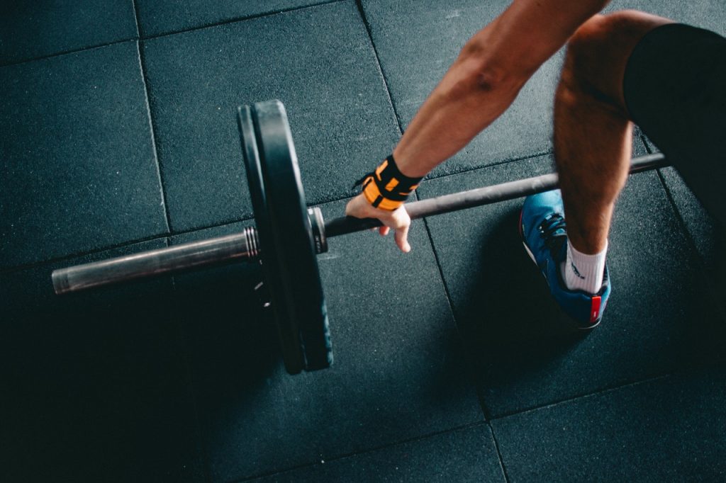 Man grabbing barbell weight for leg workout