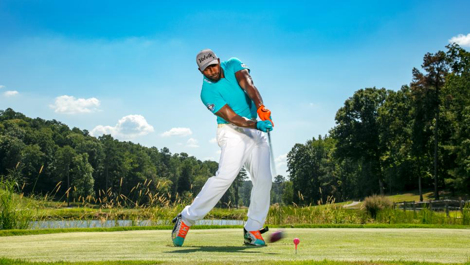 golfer hitting red golf ball down fairway